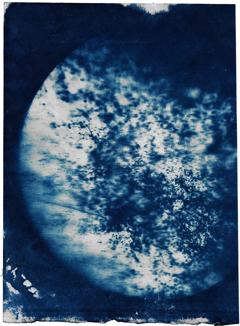 A blue and white cyanotype print from an image of air pollution particles as seen through a microscope. 