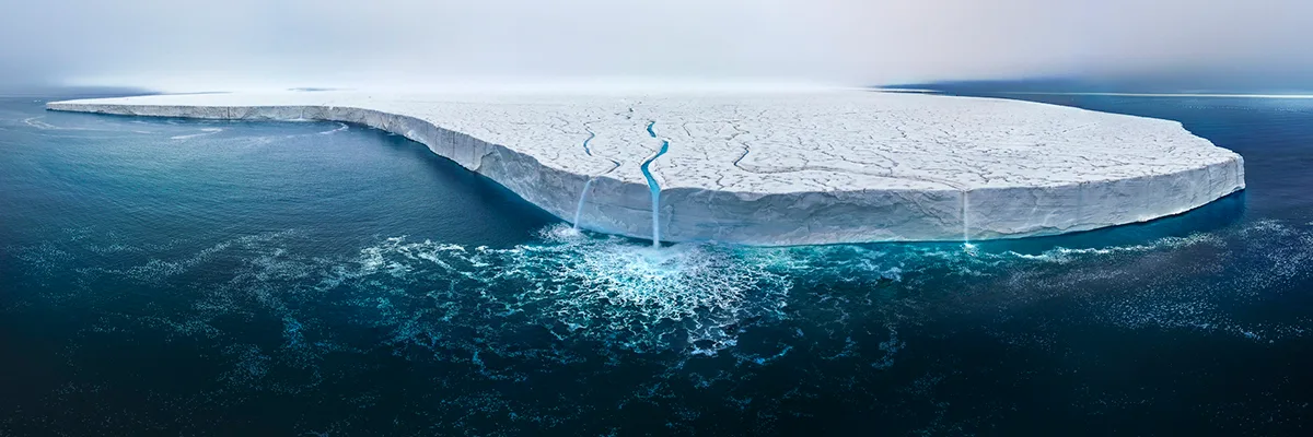 Iceberg with cracks in clear blue water.