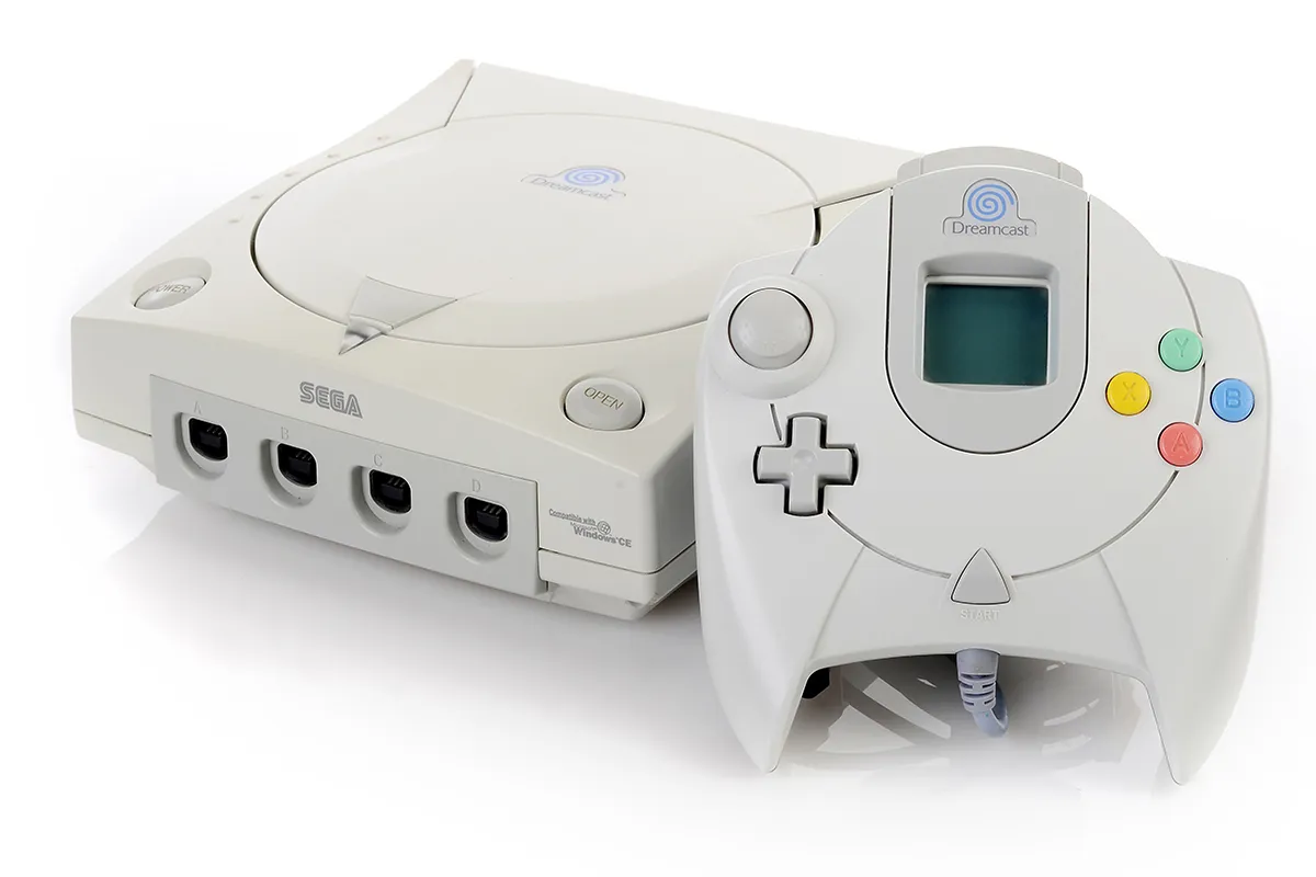 Grey computer games console and controller on white background