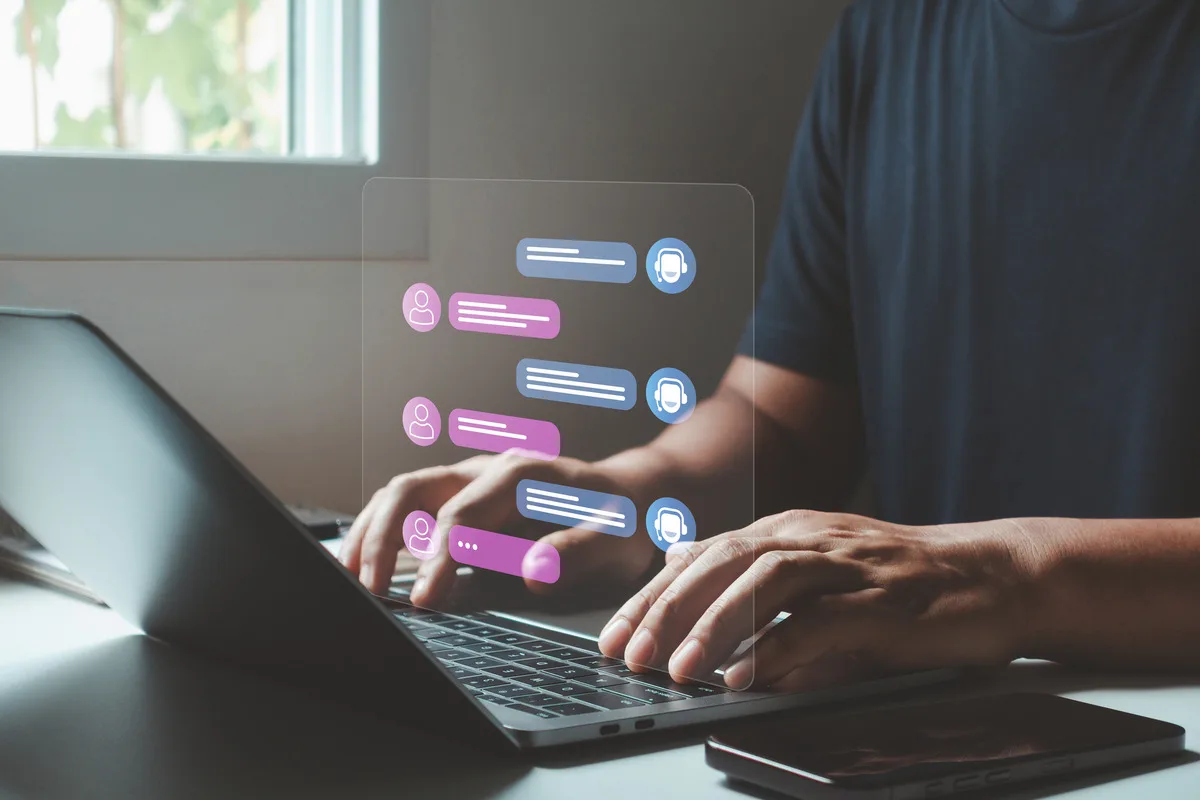 A man typing out messages on a laptop to an AI chatbot