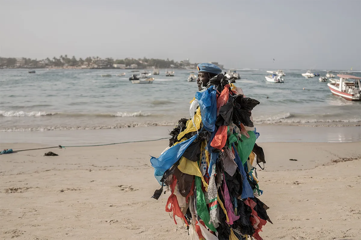 Man wearing plastic bags walks on a beach